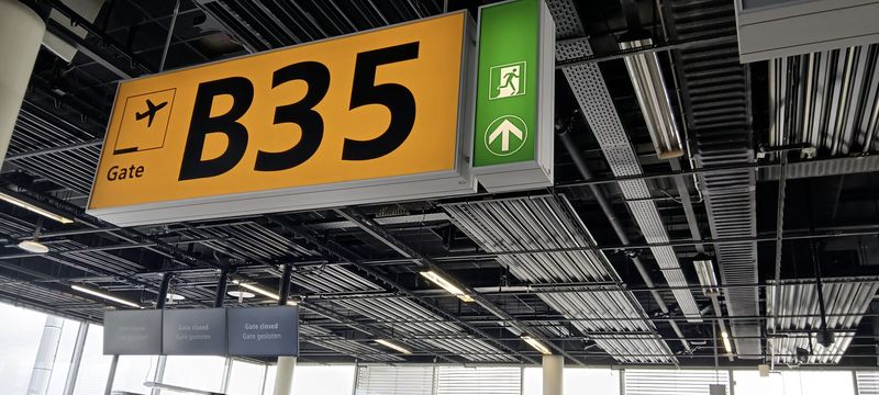 Geel bord van gate B35 op Schiphol, met daaronder borden met Gate closed