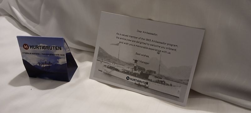 Een welkomstkaart van de Hurtigruten en een chocolaatje op het bed