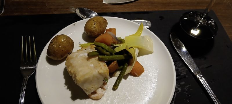 Een bord met witte vis, aardappelen en groenten